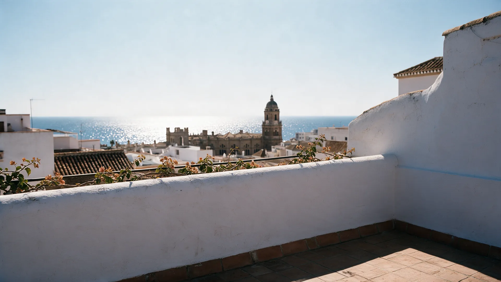 The terrace at midday in high summer, the sea glittering.